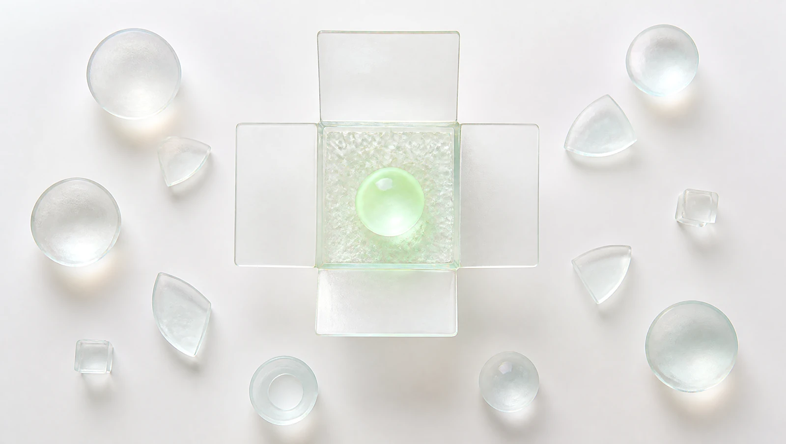 Una caja de vidrio abierta con una esfera verde adentro